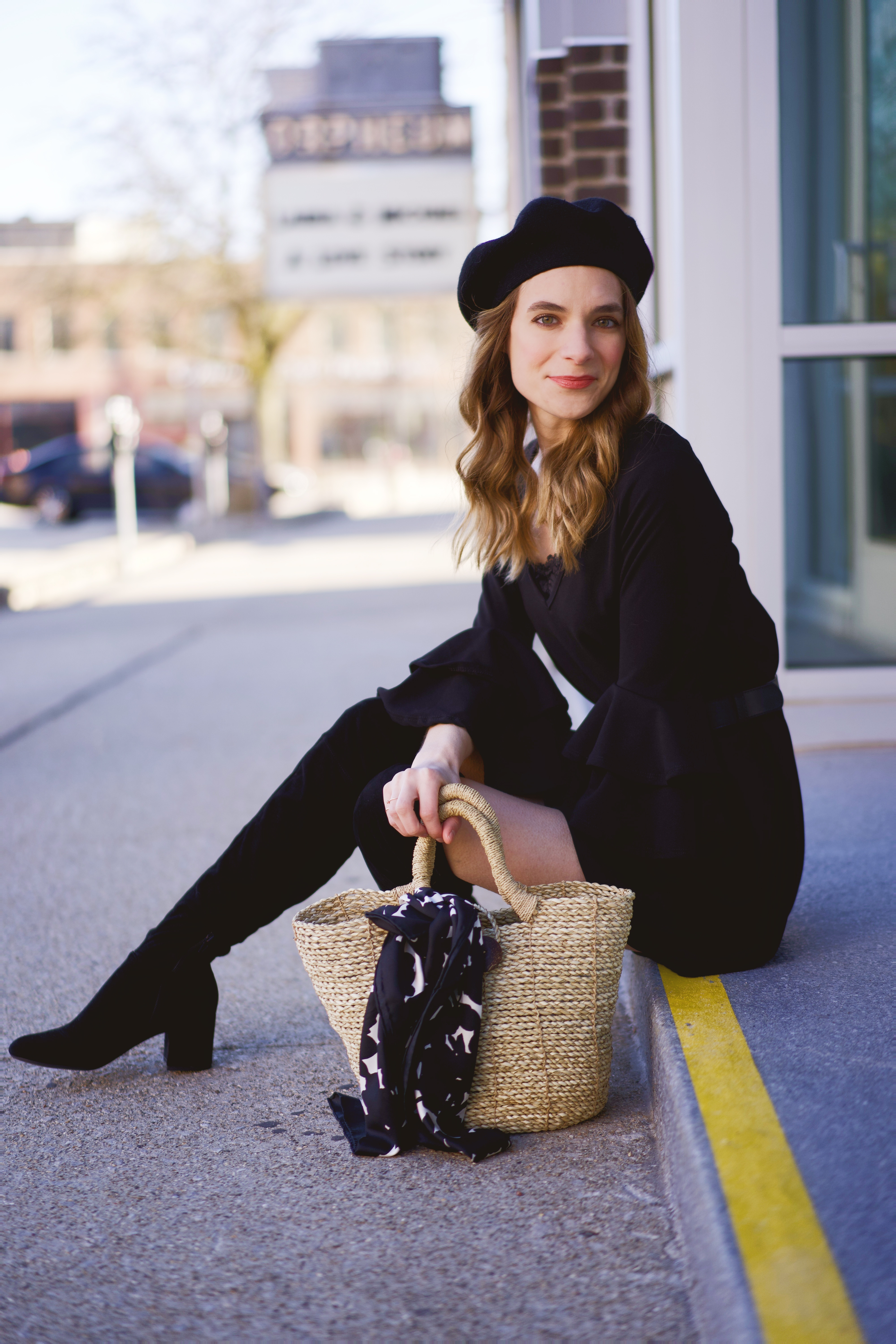 A black beret, dress, and boots paired with a straw bag