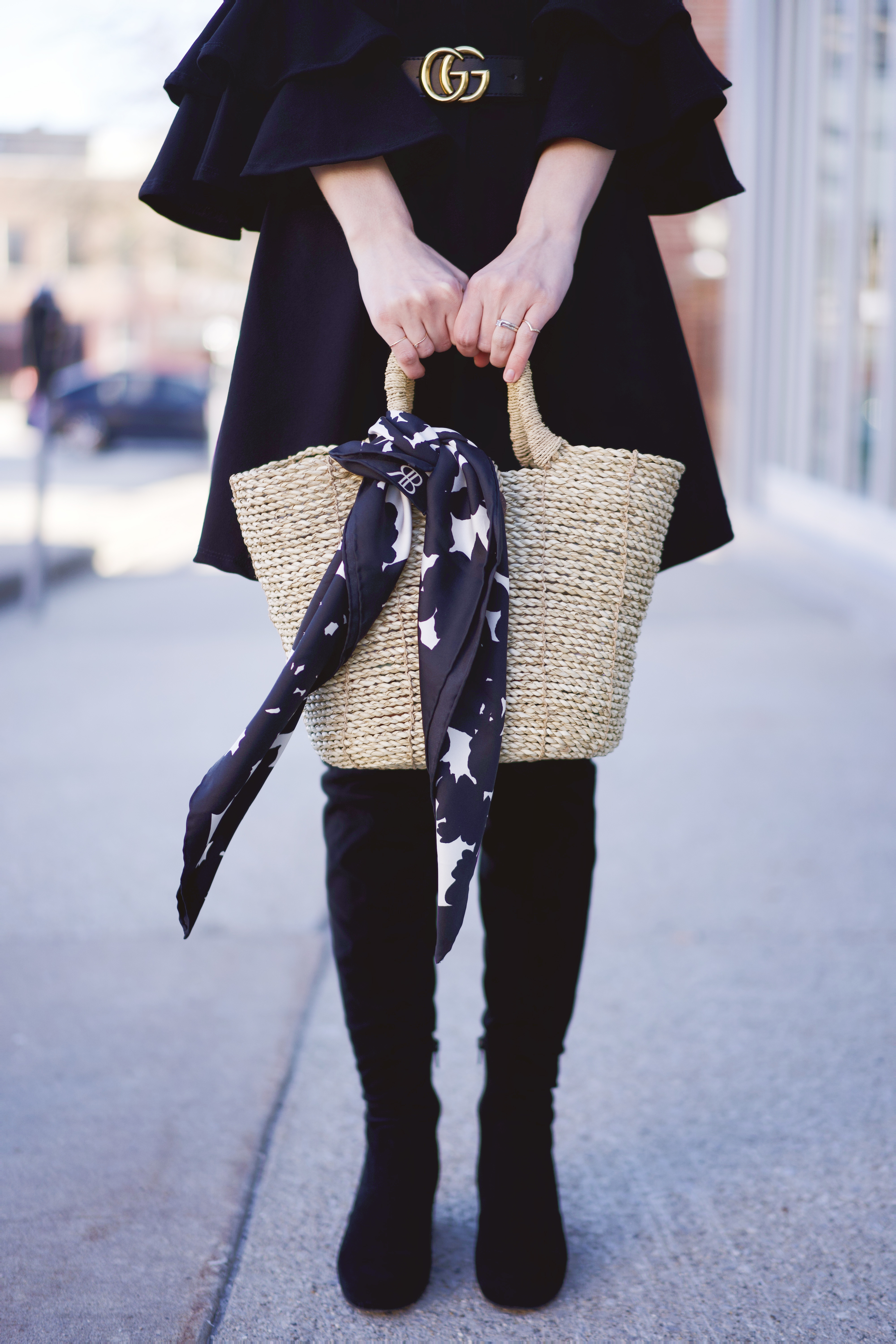 A black and white silk scarf tied onto a straw bag
